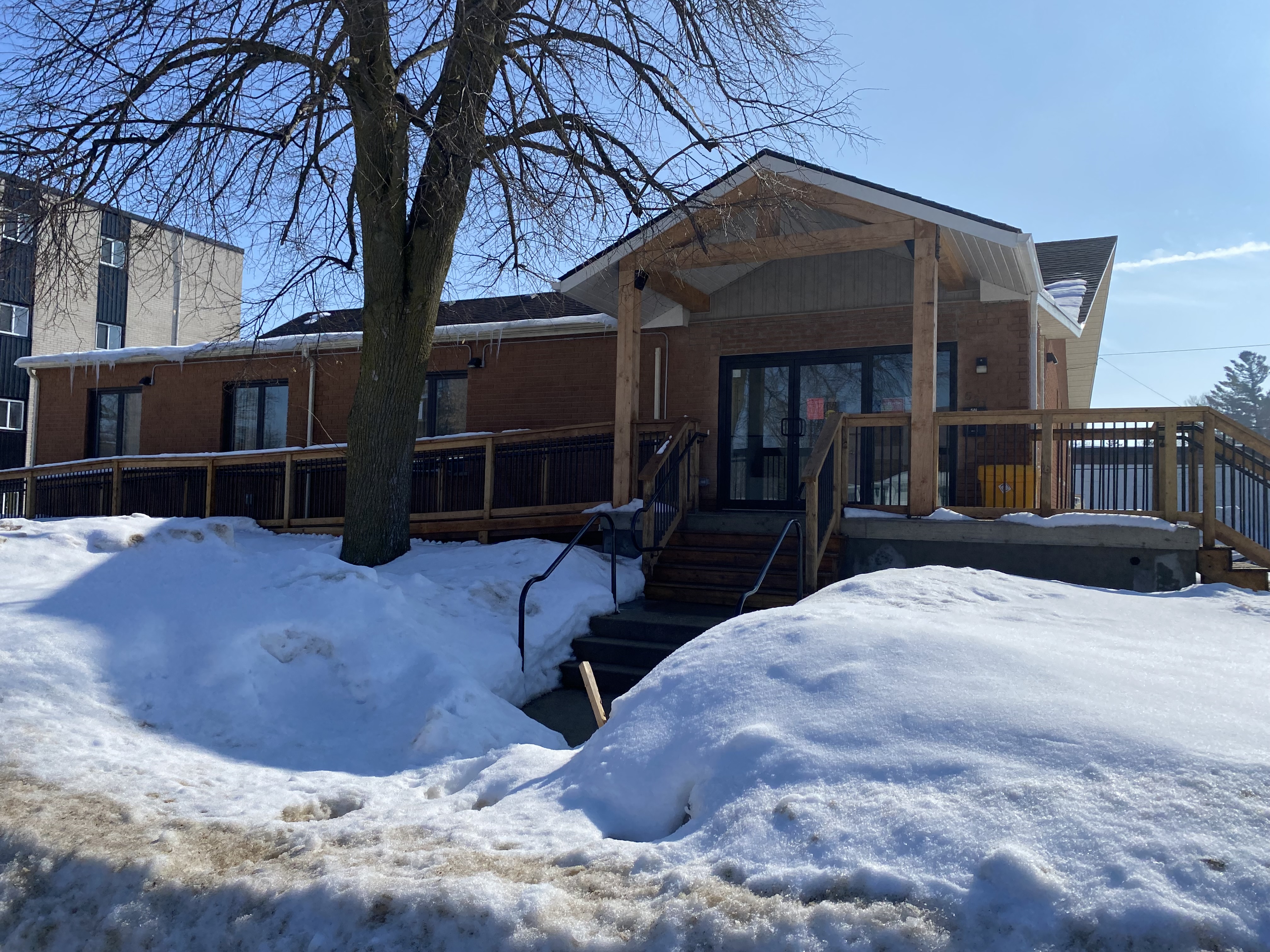 Exterior of Hanover Corps, a brick building with a covered entrance, wooden pillars, and snow-covered grounds.