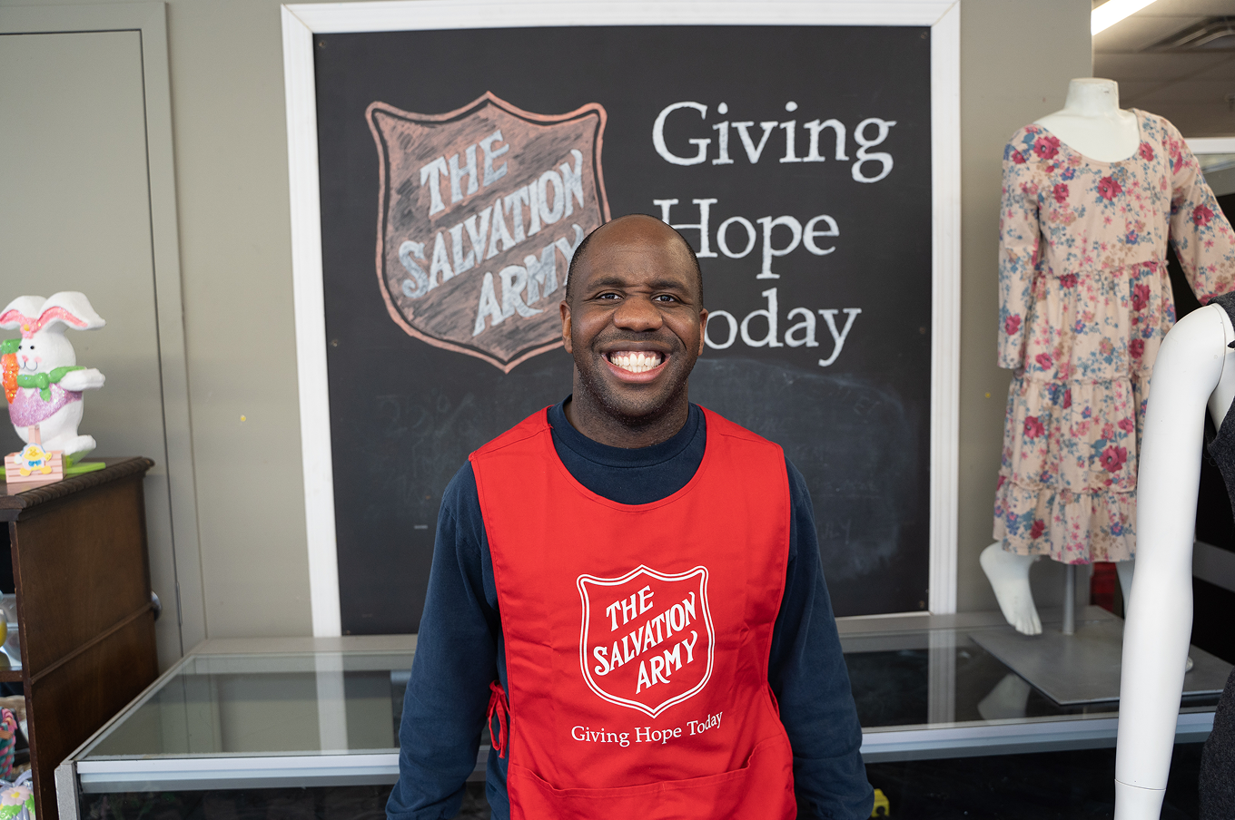 I picture of a man standing in front of a clothing display at a thrift store.