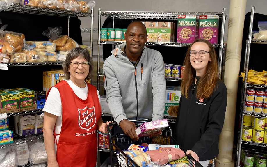 3 perople standing around a cart of food that was donated